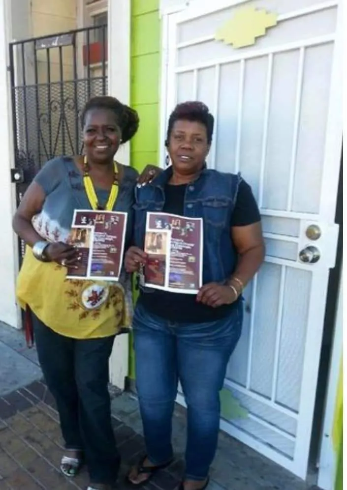 Two members holding program materials outside the transitional house