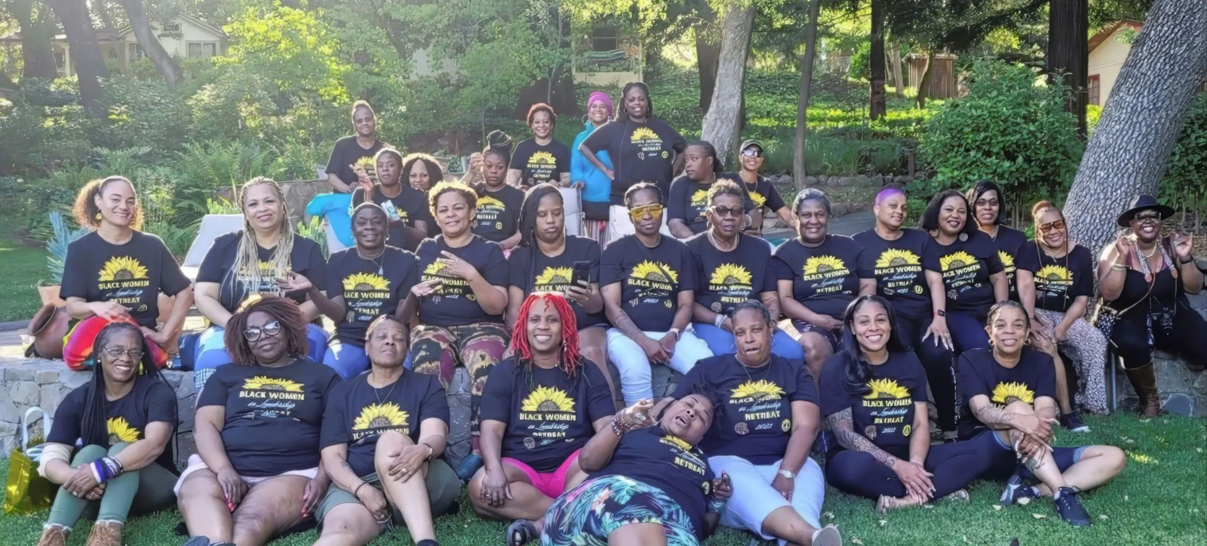 Retreat participants in Black Women in Leadership shirts, seated on a lawn