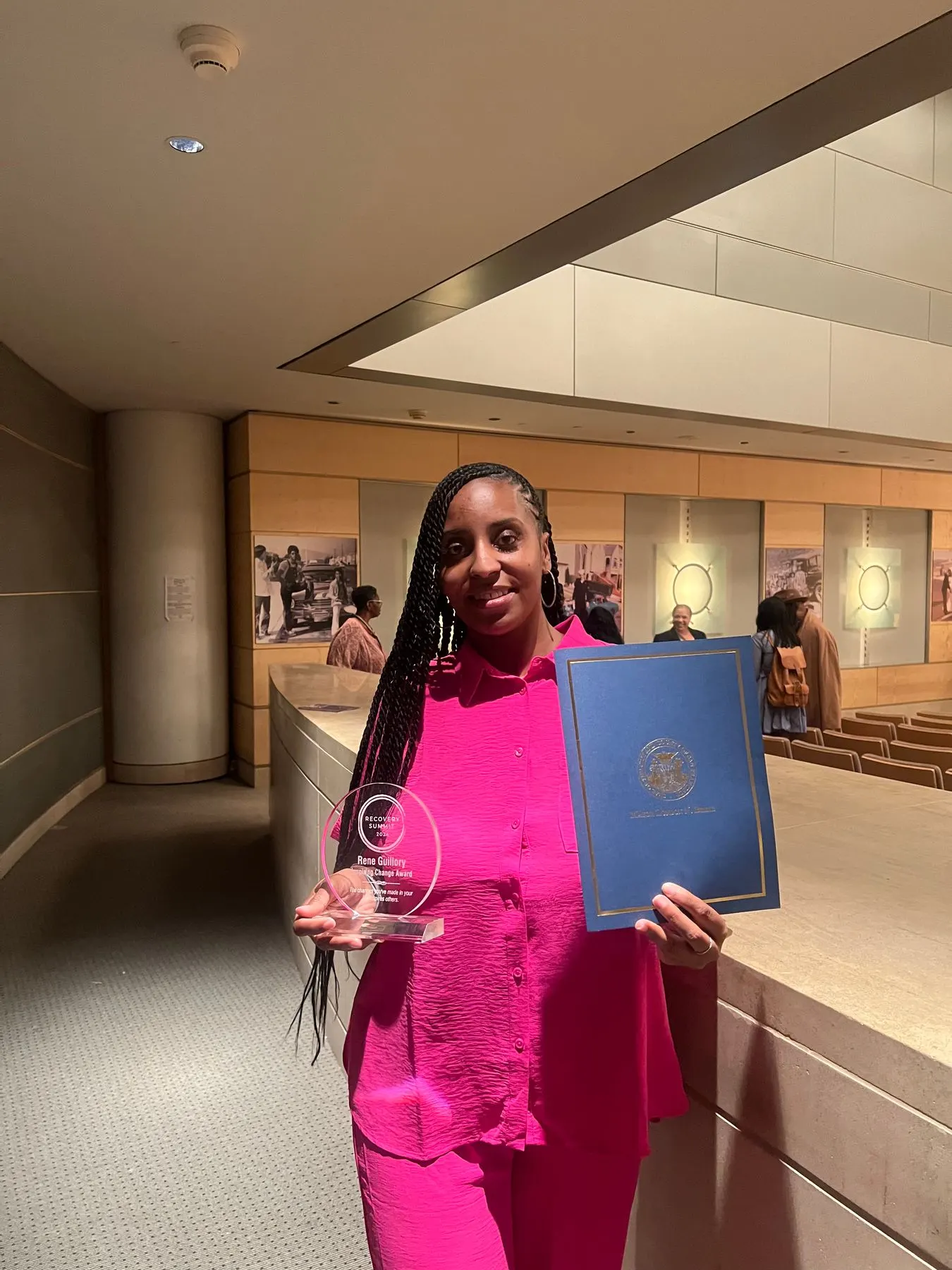 A member in pink holding her certificate